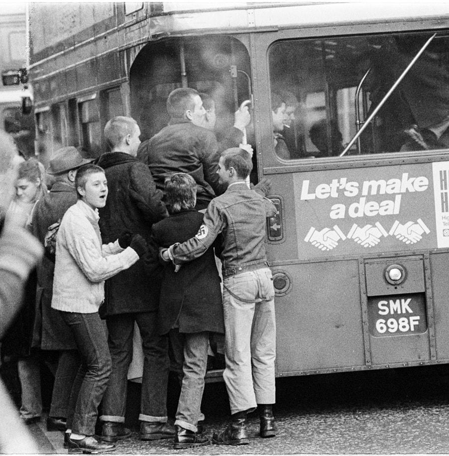 Photo by Brian de Montalk from East End '78 - Catching a Bus, black and white film photos of the East End of London in 1978 at Photospace Gallery Wellington New Zealand September-October 2022, photo of young nazi national front youths climbing onto a London bus